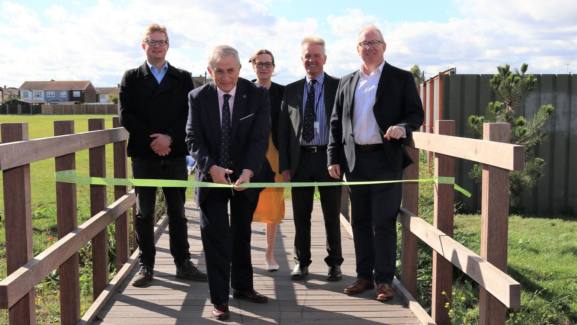 The scheme’s partners standing on the footbridge with one of them cutting a ribbon