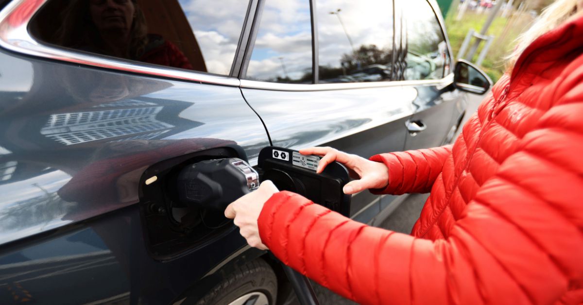 A close-up of someone charging an electric car.