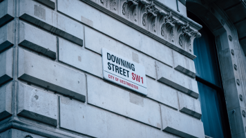 An exterior wall on Downing Street with a street-name sign in the middle