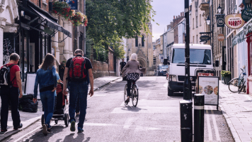 People walking and cycling down an Oxford street on a bright day