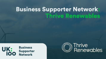 A promotional banner featuring the Business Supporter Network heading in white text overlaid on a dark, blurred background image of a lorry on a tree-lined road. The banner includes two logos: the UK100 Business Supporter Network logo on the left, showing 'UK:100' in a modern design, and the Thrive Renewables logo on the right. The overall colour scheme's dark blue-green in tone