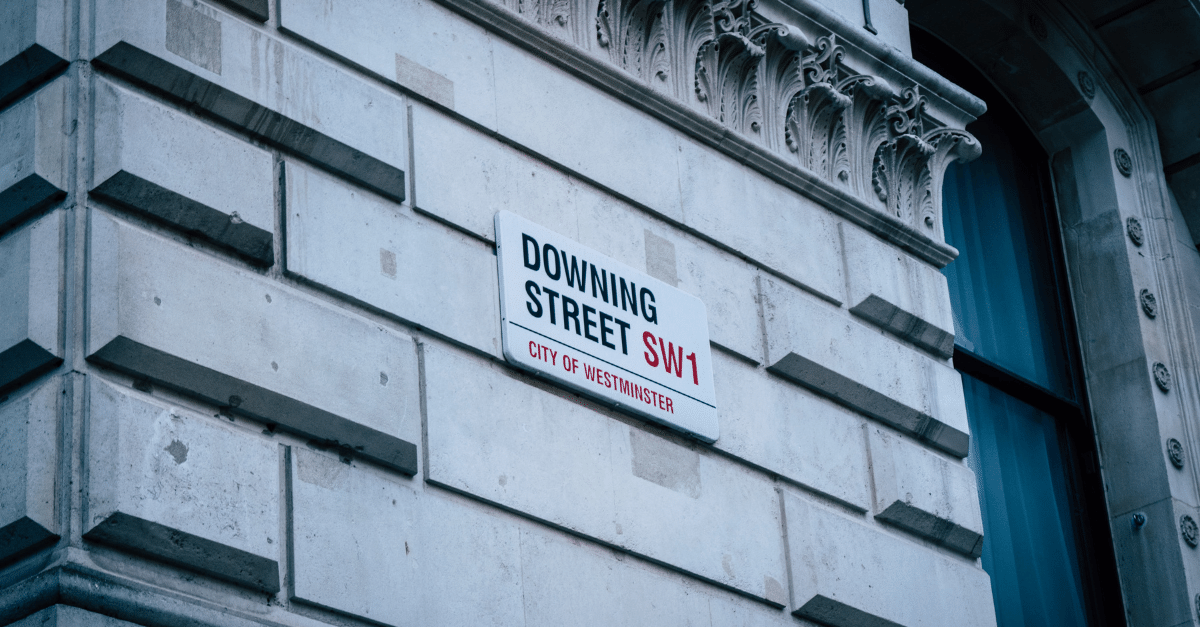 An exterior wall on Downing Street with a street-name sign in the middle