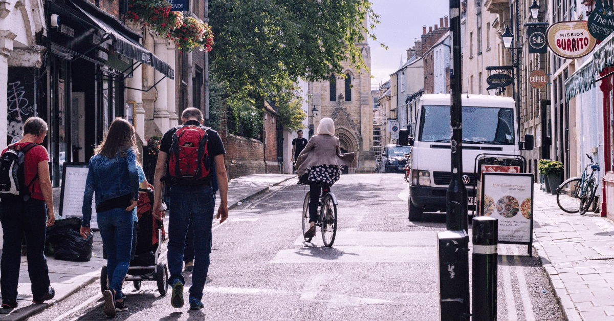 People walking and cycling down an Oxford street on a bright day